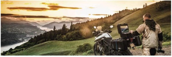 Motorcyclist overlooking a scenic hill while using his laptop in a heavy-duty laptop travel case.