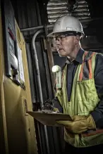 Worker using a right-angle flashlight attached to the front of his safety vest for hands-free use.